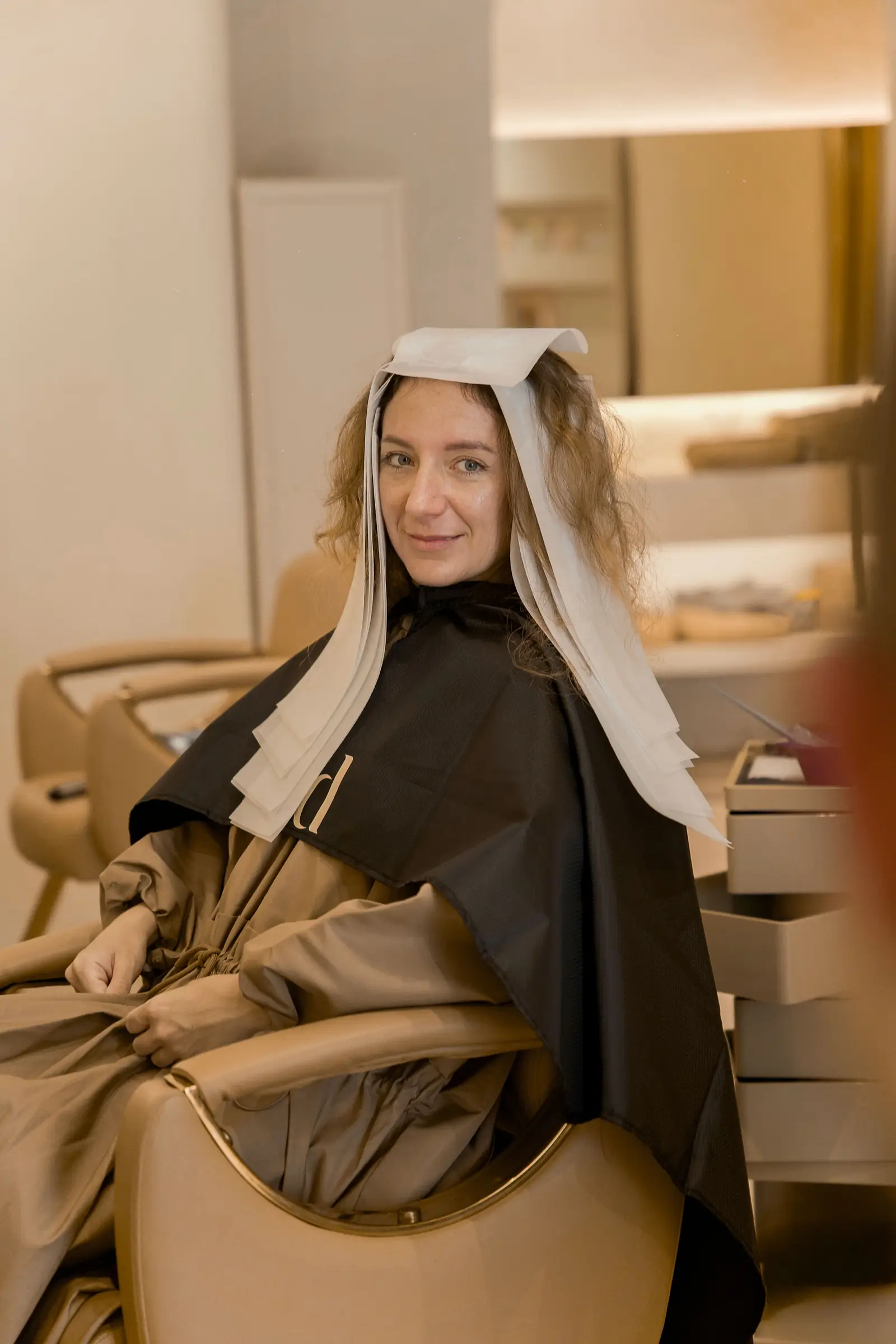A guest smiling in the chair mid-treatment at Day Hair Habit